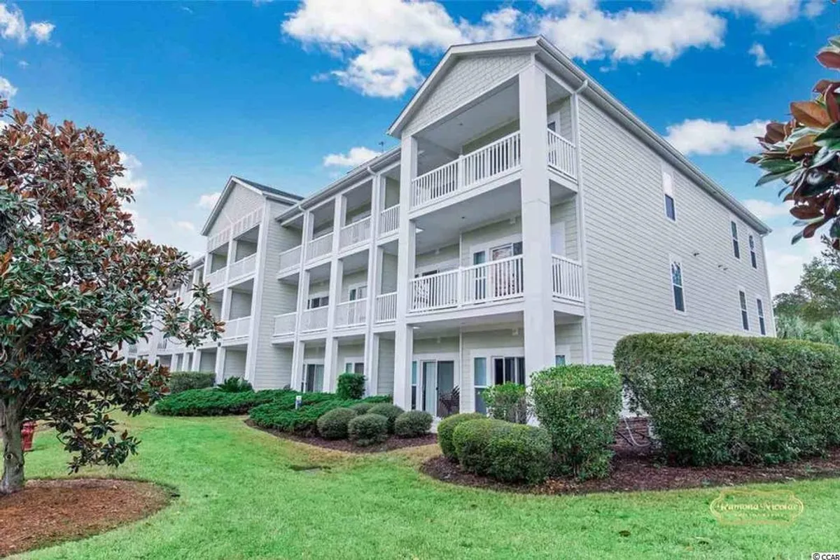 This exterior shot highlights the resort building’s elegant facade, with private balconies overlooking a beautifully landscaped garden. The welcoming atmosphere invites residents to relax outdoors or socialize in the communal green spaces.