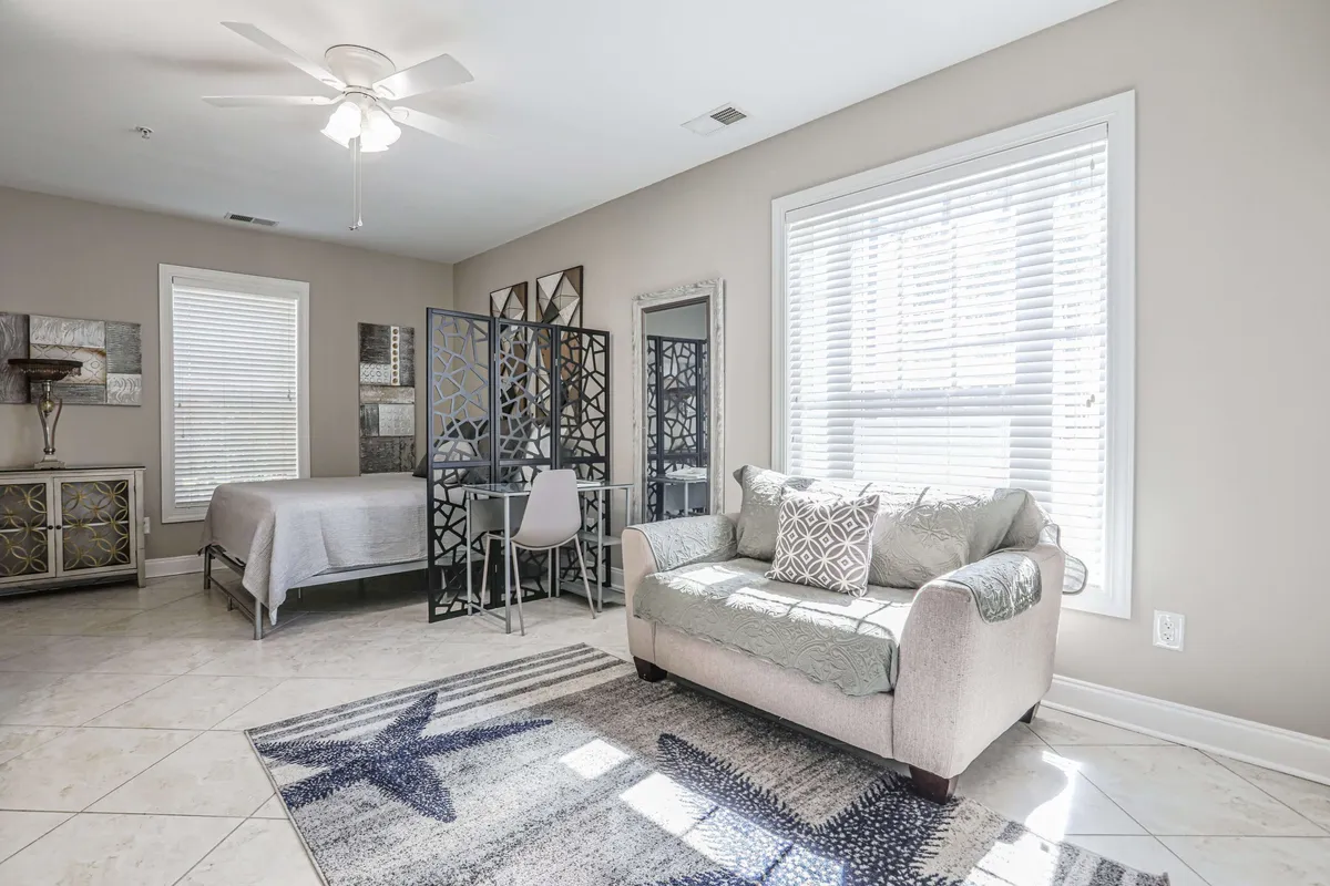 A comfortable living area with a modern sofa placed near a window, a decorative screen providing a touch of style, a dining area for enjoying meals, and tasteful artwork on the walls. Soft morning light gently brightens the space, creating a calm, inviting atmosphere ideal for relaxation or socializing.